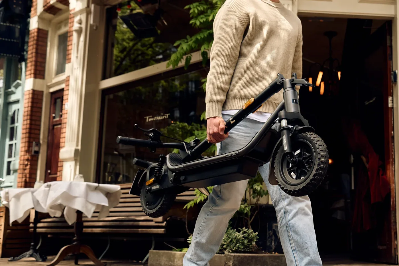 Een persoon draagt een ingeklapte Pure Electric step